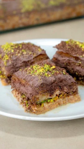 Cold baklava pieces topped with cocoa and pistachios